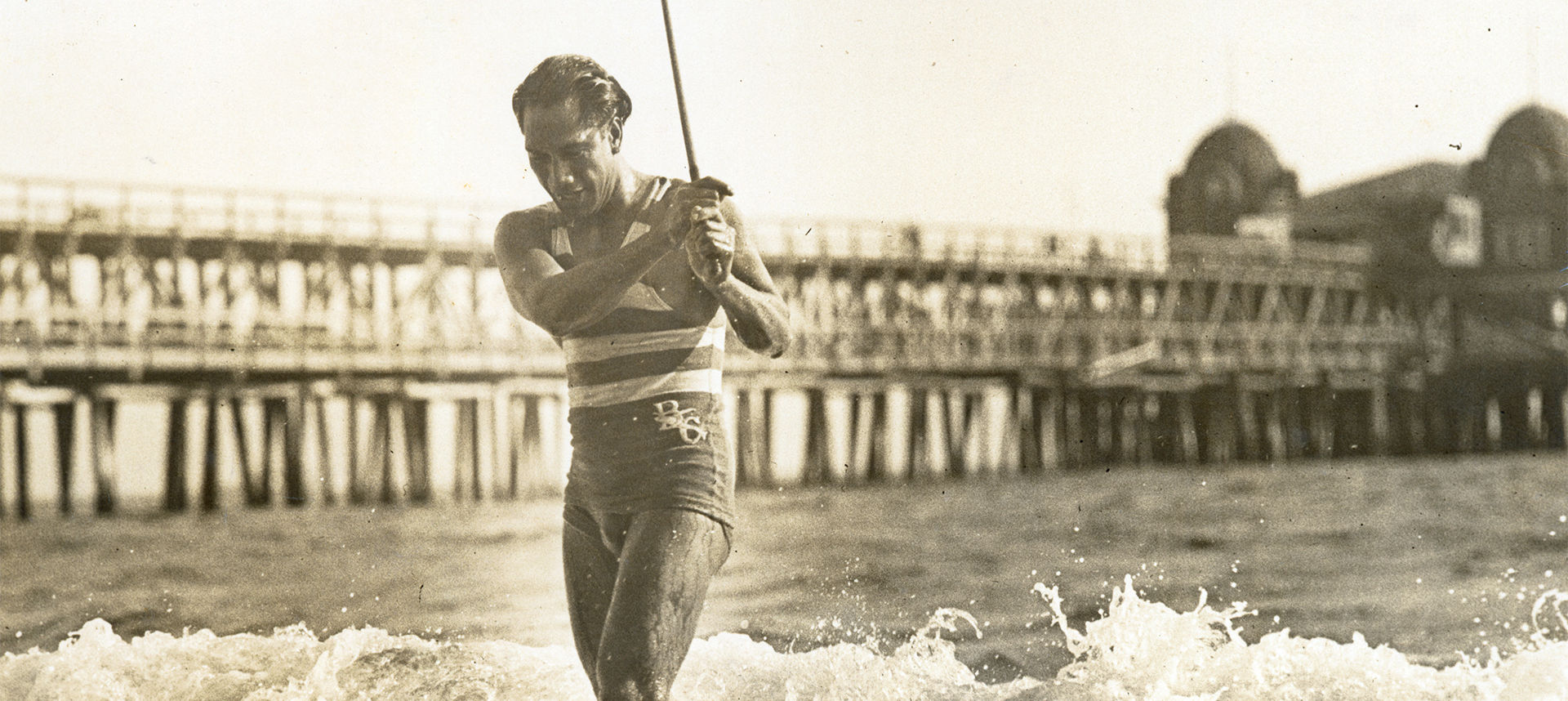 Duke exiting ocean with stick in hand